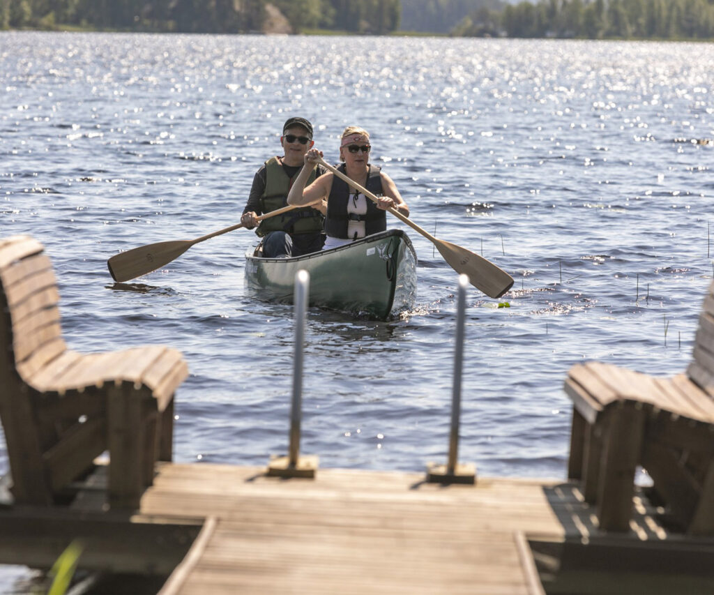 Kaksi henkilöä meloo kanotilla kohti laituria.